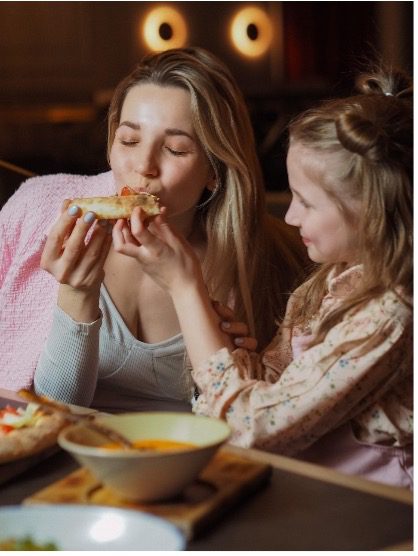 Woman and daughter eating pizza